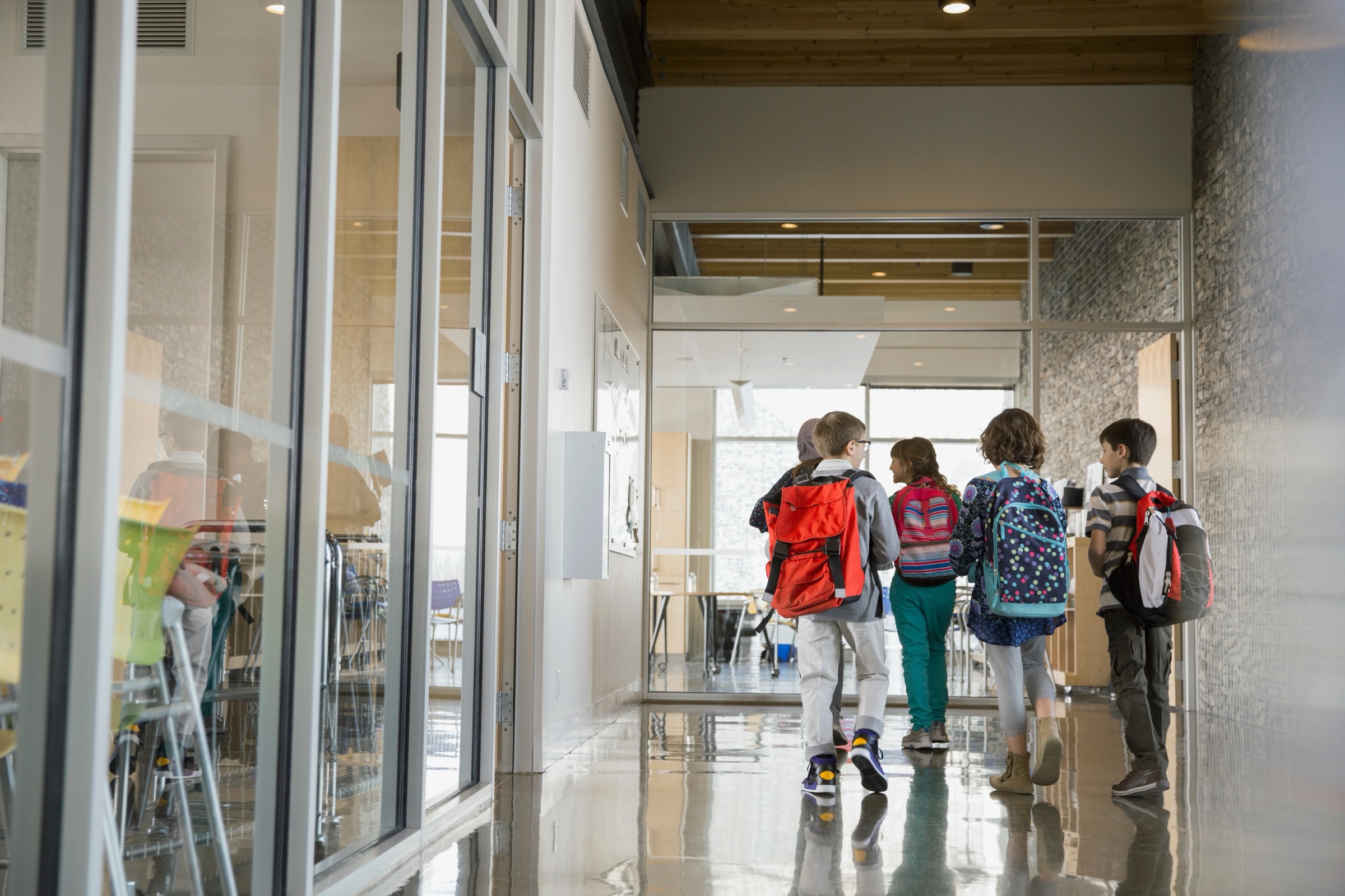 A bright, empty school hallway lined with lockers and classroom doors.